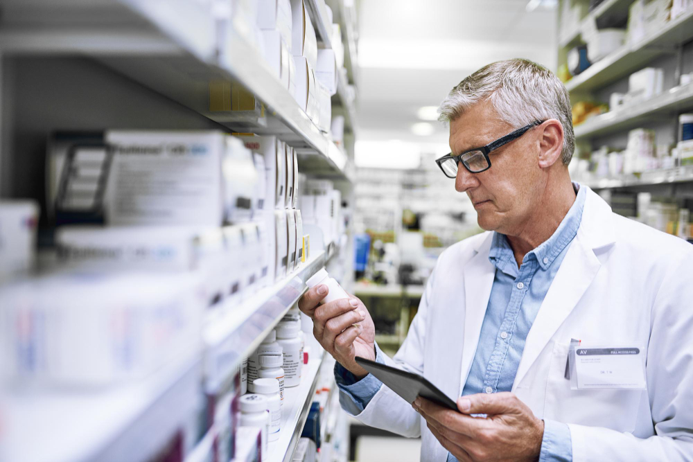Senhor com oculos na farmacia com o medicamento na mão; 